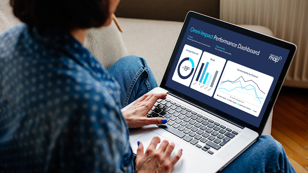 A woman sits and uses her laptop, which displays various charts and graphs.