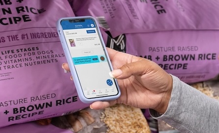 A woman uses the Sam's Club Scan and Go app to scan a bag of dog food.