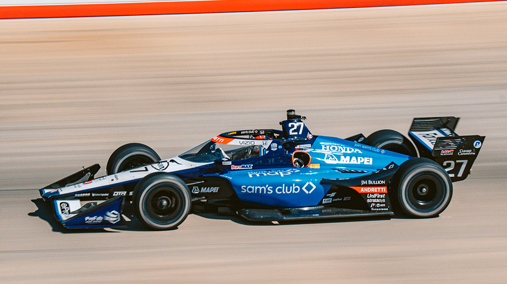 A mother and daughter smile as they push a cart and shop together inside of a Sam's Club.