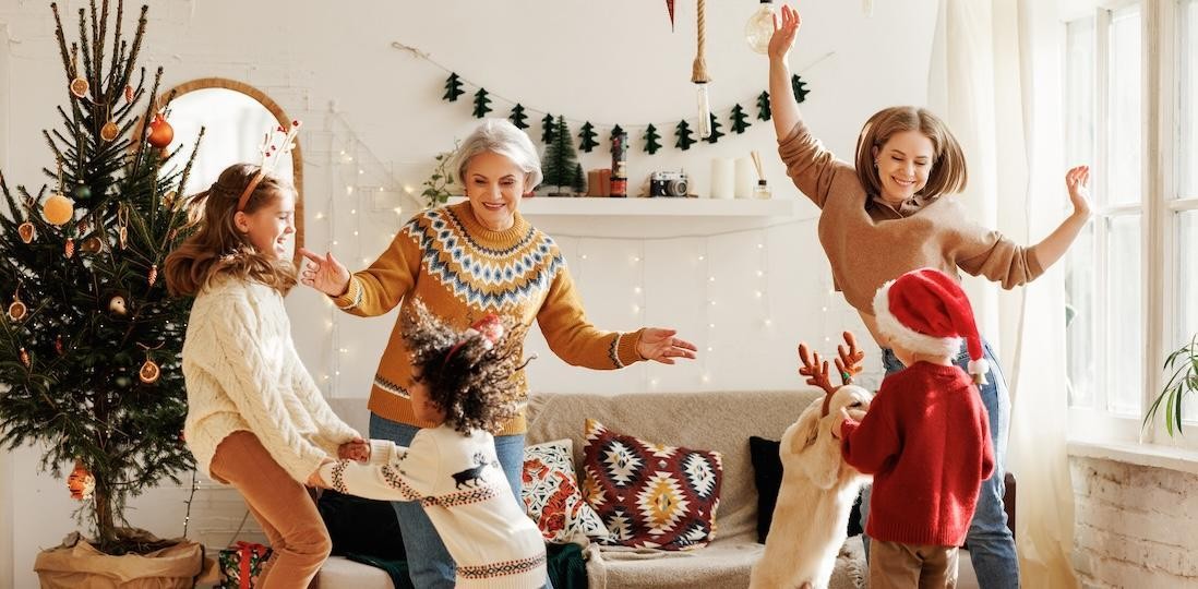 A family joyfully dances around a decorated Christmas tree, celebrating the festive season together.