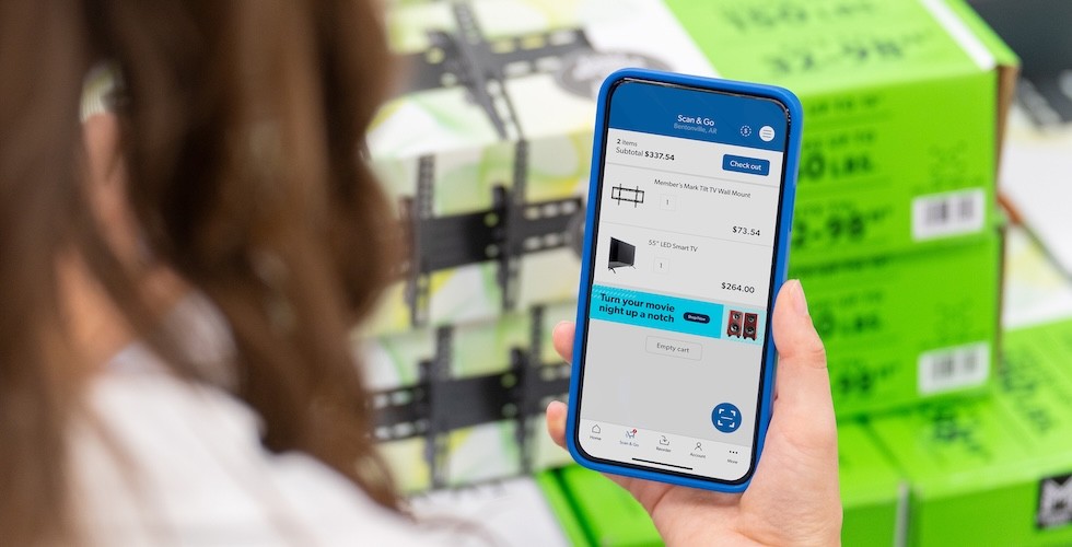 A woman uses the Sam's Club Scan and Go app to scan a barcode on a box using her mobile phone.