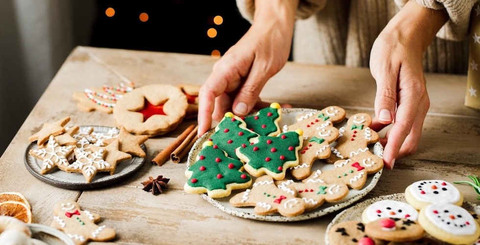 A woman presents a plate of freshly baked cookies on a table.