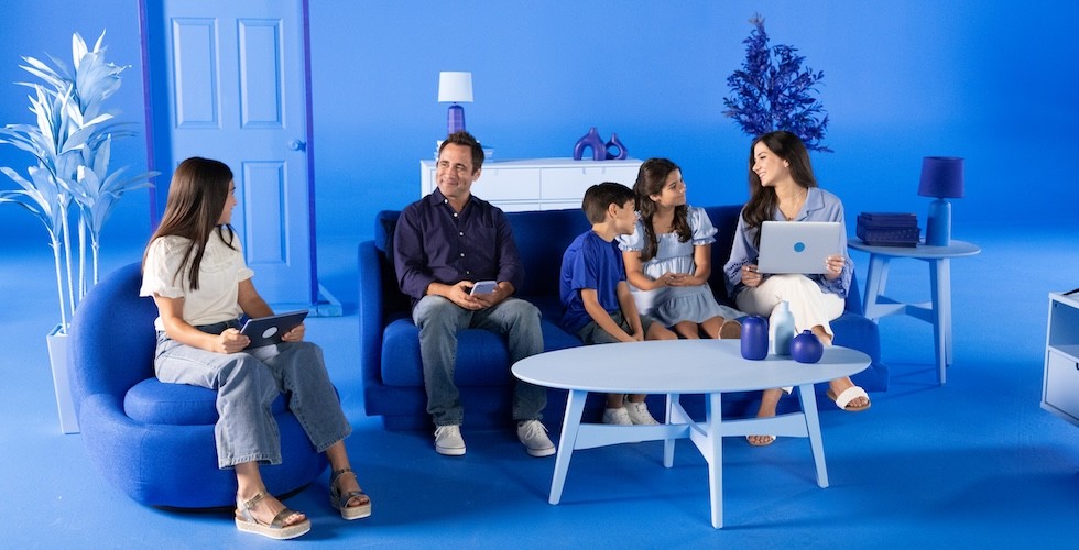 A happy family wearing various shades of blue sits in a room styled with blue furniture and decor.