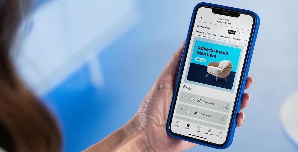 A woman holding a mobile phone with an illustration of the Sam's Club Scan & Go app displayed on screen.